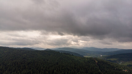 Majestic Mountains, Lush Green Forests, And Dramatic Clouds With The Sun Casting A Golden Glow. Aerial View Capturing The Stunning Beauty Of Nature From A Bird’s-Eye Perspective.