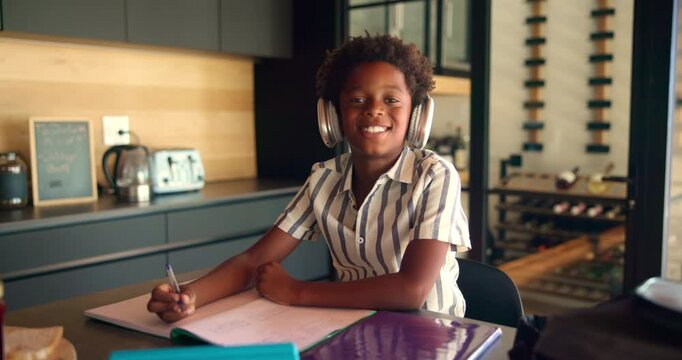 Homework, headphones and face of child with notebook writing for learning, education and lesson. School, portrait and African boy with music with notebook for studying, knowledge and development