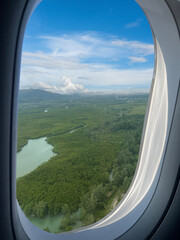 View from window of airplane to forest and lake with blue sky background