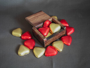 red and gold heart shaped chocolates in a wooden box