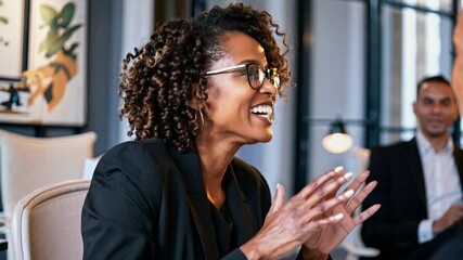 Video of a professional woman engaging in a lively conversation in an office setting, showcasing a warm, friendly atmosphere. Close-up camera angle.