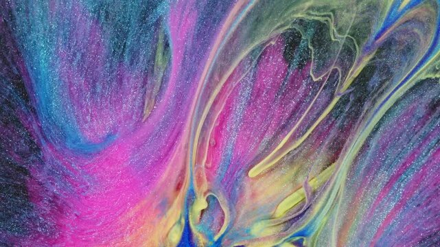A close-up of swirling rainbow-colored ink in water, creating an abstract pattern with glitter and sparkle effects. The video background is a mix of neon colors, providing space for design elements