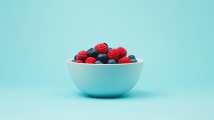 A vibrant bowl filled with fresh raspberries and blueberries against a bright blue background.