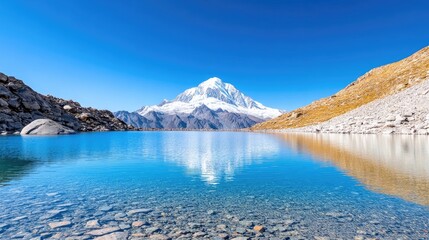 Obraz premium Majestic snow-capped mountain reflecting in a serene lake under a clear blue sky
