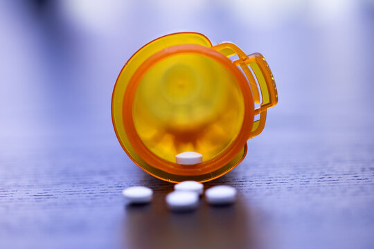 white pills in a yellow prescription bottle on the table
