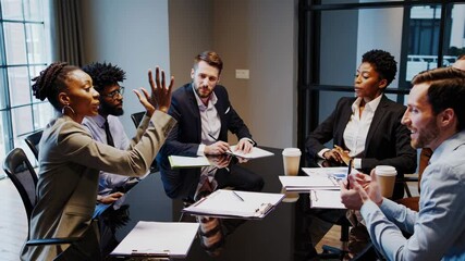 Video of a diverse business meeting with professionals discussing around a table. The style is corporate and engaging. Shot from a wide-angle camera angle.