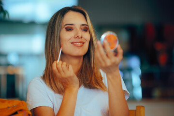 Happy Woman Putting on lip Gloss in a restaurant. Girlfriend getting ready for her date with last...