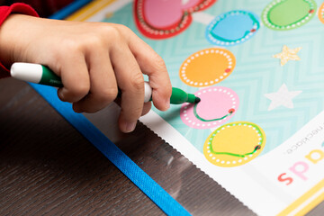 a toddler tracing circles and lines on a worksheet with markers for preschool