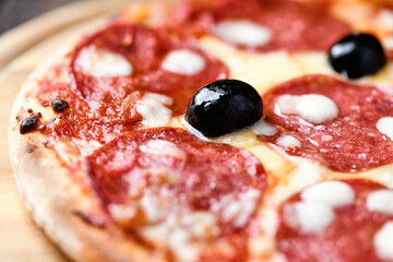 Pizza with salami and mozzarella cheese. Wooden background. Soft focus. Close up.	