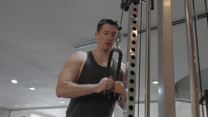 A man working out in the gym using a cable machine, focusing on upper-body strength training. Concept of fitness, health, and physical activity.