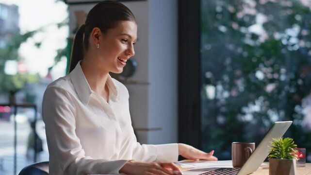 Positive consultant video calling by laptop making notes in notebook closeup.