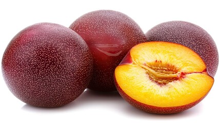 Fresh plums displayed with one cut open, showcasing vibrant yellow flesh, on a white background