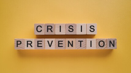 Obraz premium Crisis prevention wooden letter blocks on a bold yellow background.