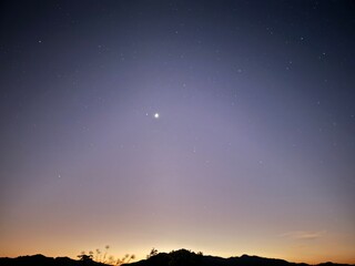 Fototapeta premium A stunning twilight scene with a gradient of colors over a mountainous landscape, creating a calm and serene view