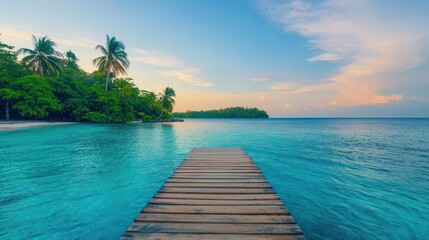 Naklejka premium Wooden dock extending into clear blue water towards a tropical island with lush greenery and sandy beach