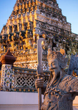 Guardian statue in front of Wat Arun, or Temple of the Dawn, a Buddhist temple in Bangkok, Thailand, at sunset