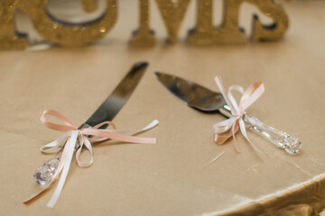 wedding cake cutting utensils with pink ribbon on the table next to the cake