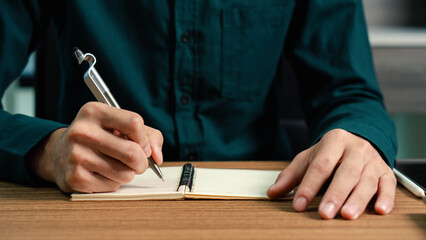 Businessman writing note with pen inspired ideas list on notepad while working on laptop computer in office, event planning, Planner plan schedule calendar and reminder agenda