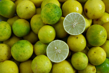 Two half-lime textures placed on a yellow lime background. Top view ripe lime texture. Natural, sour ingredient, and home cooking for Asian cuisine wallpaper. Food texture background of yellow limes.