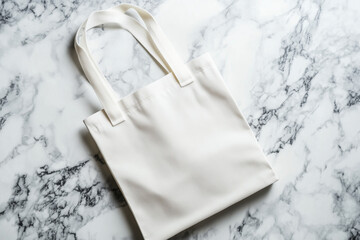 A white tote bag lies on a marble table, viewed from above. The tote is blank, with no designs or text, resembling a mockup. The lighting is bright and even, creating a clean and minimalistic look