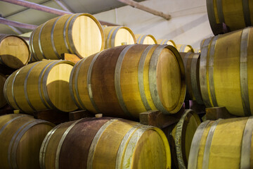 Stacked wooden wine barrels in a winery cellar, highlighting traditional wine aging and storage...
