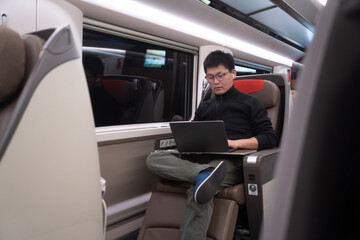 asian man using laptop on train