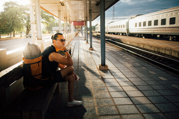 Man tourist backpacker sit at the platform wait for the train.