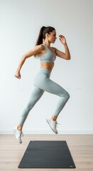 Fototapeta premium Fitness workout. Sport woman fitness trainer exercising, on white background. Full length vertical shot of sporty girl in light stylish trendy sportswear running on spot, warming up at studio