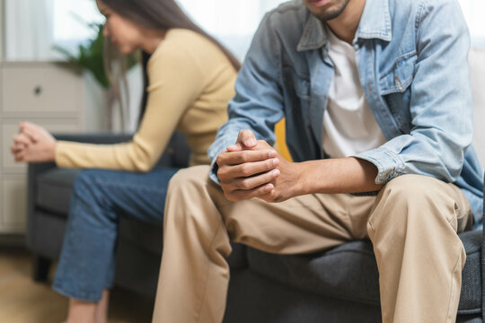 Family problem concept. Tension in relationship between married couple, husband and wife staying sitting separate after quarrel in the living room.