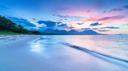 Fototapeta premium A serene beach with mountains in the distance and a sky filled with the soft colors of twilight. 