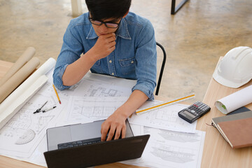 Architect and engineer working on a laptop with blueprints