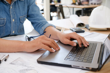 Architect and engineer working on a laptop with blueprints