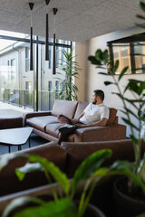 Person lounging on couch by the panoramic window in hotel lobby
