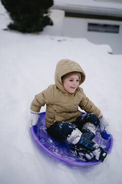 Child in winter sledding down a snowy hill