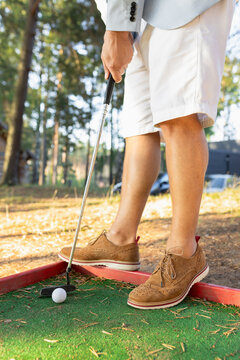 Stylish man in white shorts and suede shoes holding mini golf club