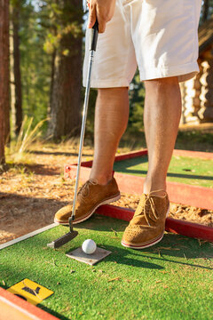 Closeup view of mini golf player with golf club and ball