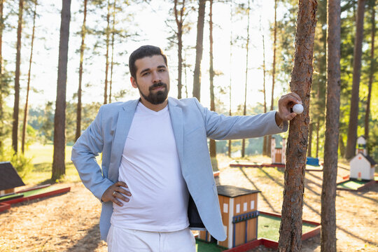 Portrait of mini golf player with ball against forest court