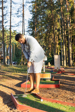 Focused stylish mini golf player on court in forest