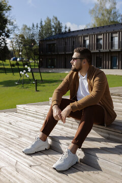 Young adult stylish man enjoying sunlight on wooden terrace