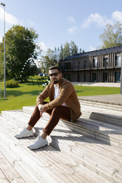 Handsome young adult man sitting on outside terrace stairs