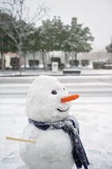 Smiling snowman with a scarf and carrot nose in a snowy urban setting