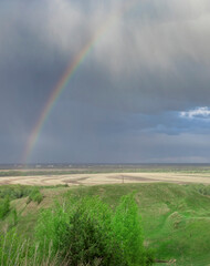 Rainbow is seen in the sky above a field