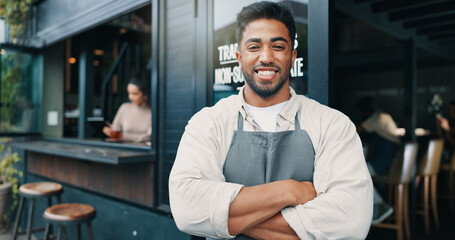 Portrait, coffee shop and man with arms crossed, confidence and waiter with friendly service, smile and apron. Face, people and employee with skills, cafe and hospitality with welcome and barista