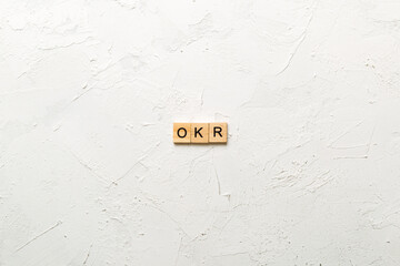 OKR word written on wood block. abbreviation of Objective Key Results text on cement table for your...
