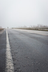 Cars on highway in the fog. Bad weather on the road. Road on foggy day in perspective with copy space. Driving conditions concept. Ghostly misty road. Caution and danger on the road. 