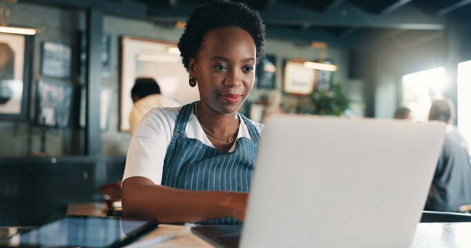 Typing, laptop and planning with black woman in cafe for product inventory, supplier contact or budget update. Menu discount, restaurant review and small business owner with employee in coffee shop