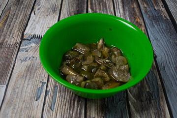 A green plastic bowl contains green eggplant vegetable dishes. Serving simple home cooking but appetizing.