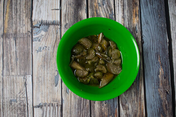 A green plastic bowl contains green eggplant vegetable dishes. Serving simple home cooking but appetizing.
