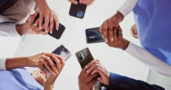 Doctor, hands and meeting below with phone for data sync, research or telehealth at hospital. Low angle, group or healthcare employees in circle with mobile smartphone for sharing network at clinic