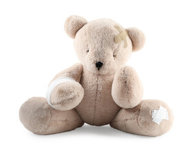 Teddy bear with bandages and adhesive medical plasters isolated on white